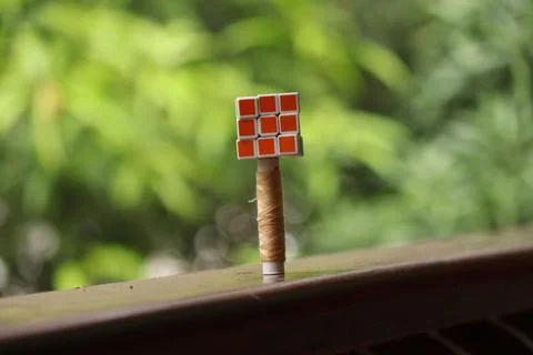 A Rubics cube placed over a sewing thread placed in a dusty floor Stock Photos