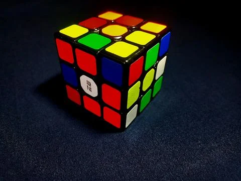 A Rubik's Cube emerges in three-dimensional form against a stark black backdrop, Stock Photos