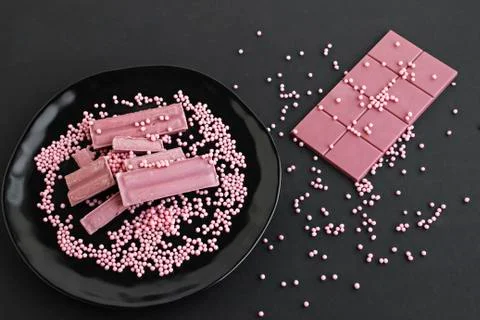 Ruby chocolate is on black porcelain plate with decoration candies. Foto stock
