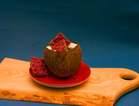 Ruby chocolate pieces inside of half coconut. blue background Stock Photos