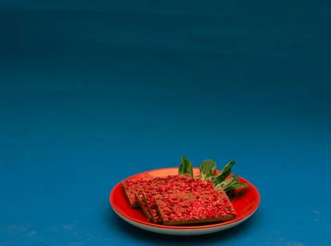Ruby chocolate pieces on red plate. Blue background Stock Photos