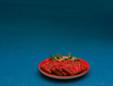 Ruby chocolate pieces on red plate. Blue background Stock Photos