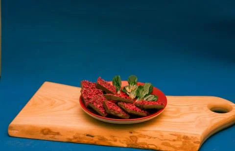 Ruby chocolate pieces on red plate on wooden chopping board. Blue background Stock Photos