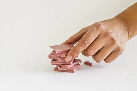 Ruby chocolate sliced and hand stacking up on white background Foto stock