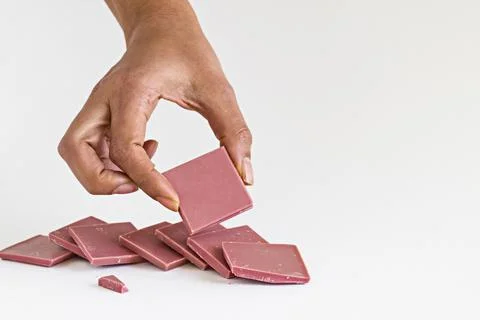Ruby chocolate sliced and hand holding one piece on white Stock Photos