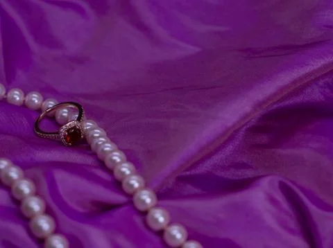 Ruby ring with pearl necklace on pink surface 스톡 사진