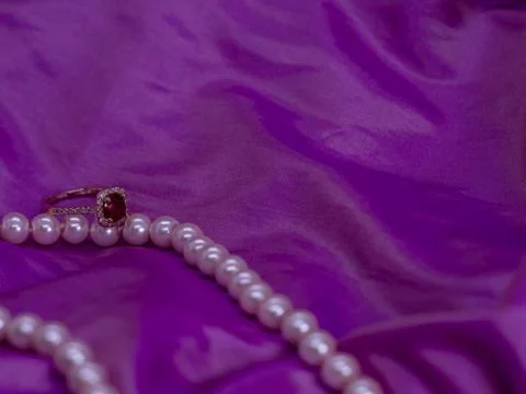 Ruby ring with pearl necklace on pink surface Stock Photos