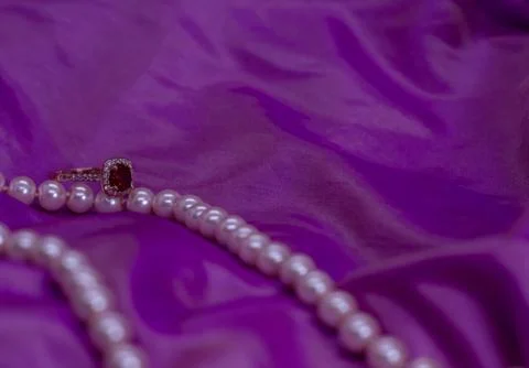 Ruby ring with pearl necklace on pink surface 库存照片