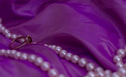 Ruby ring with pearl necklace on pink surface Stock Photos
