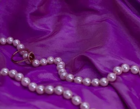 Ruby ring with pearl necklace on pink surface 스톡 사진