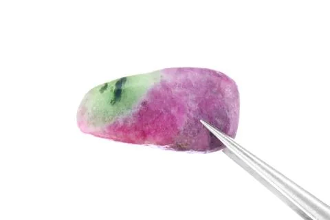 Ruby zoisite jewel stone texture in tweezers on light surface background. Mac Stock Photos