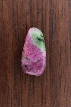 Ruby zoisite jewel stone texture on brown varnished wood background. Macro cl Stock Photos