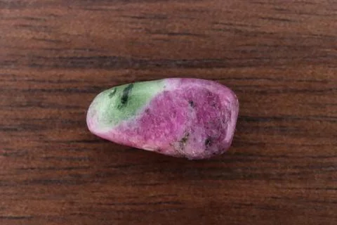 Ruby zoisite jewel stone texture on brown varnished wood background. Macro cl Stock Photos