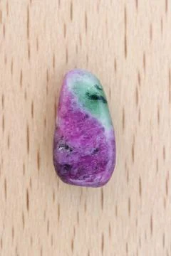 Ruby zoisite jewel stone texture on light varnished wood background. Macro cl Stock Photos