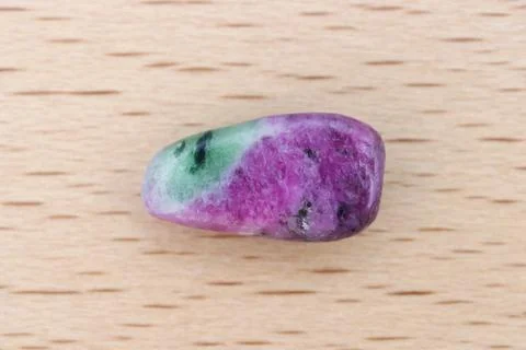 Ruby zoisite jewel stone texture on light varnished wood background. Macro cl Stock Photos