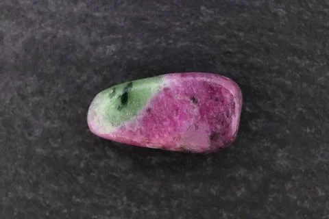 Ruby zoisite jewel stone texture on black stone background. Macro closeup. Stock Photos