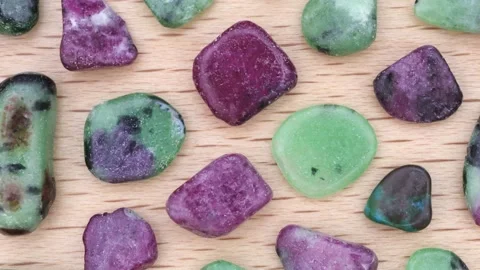 Ruby zoisite rare jewel stones texture on light varnished wood background. Mo Stock Footage 221097462