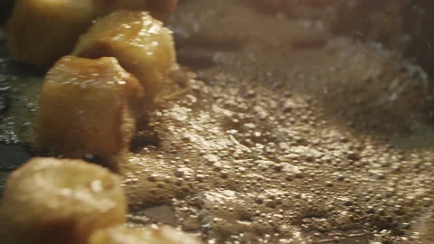 Ruddy banana slices are fried in sizzling and foaming oil in a hot pan Video stock 154147853