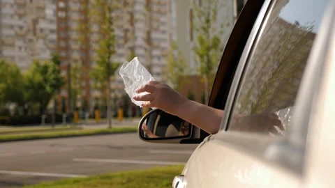 A rude woman throws plastic garbage out of a car window in the city. Stock Footage 315380567
