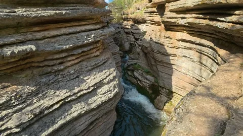 Rugged canyon walls frame rushing water below. Slowmotion. Rosomac Stock-Footage 335536109
