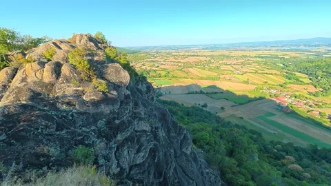 Rugged cliff edge overlooks sprawling green fields. Boracki krs Serbia 動画素材 345004531