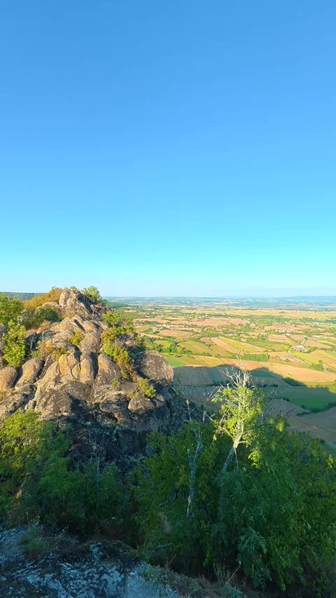 Rugged cliff tops frame a vast, sunlit countryside. Boracki krs Serbia Vertical 動画素材 345006106