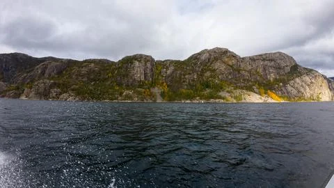 Rugged Cliffs and Calm Waters Under Overcast Sky Stock Photos