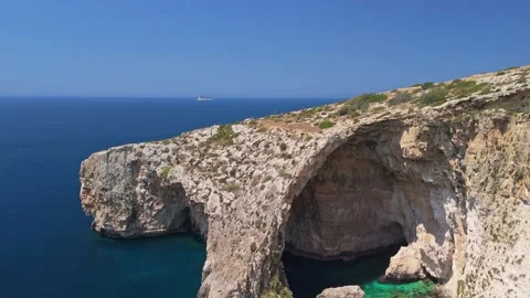 Rugged cliffs and a sea arch at Malta's Blue Grotto rise over azure waters Stock Footage 337000938