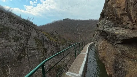 Rugged cliffs frame a narrow canal path. Vucjanka Canyon, Serbia Stockbeeldmateriaal 332171716