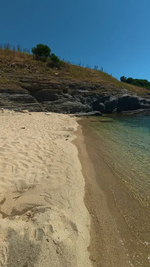 Rugged cliffs frame a secluded, peaceful beach. Trani Ammouda, Greece. Vertical Stock Footage 339629318