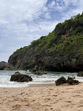 Rugged cliffs meet gentle waves beside sandy shores Stock Photos