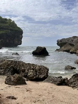 Rugged cliffs meet gentle waves beside sandy shores Stock Photos