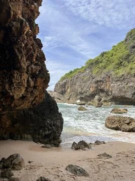Rugged cliffs meet gentle waves beside sandy shores Stock Photos