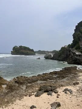 Rugged cliffs meet gentle waves beside sandy shores Foto stock