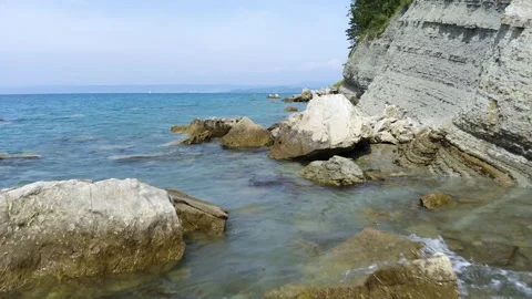 A rugged coast of towering cliffs and scattered boulders meets the ocean. Stock-Footage 259074660