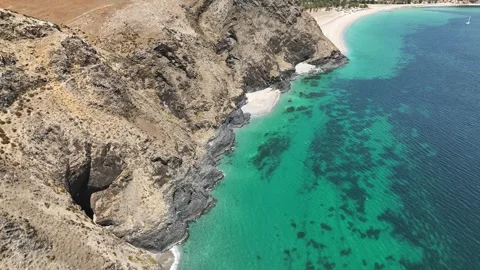 Rugged coastal cliffs and coves above a calm turquoise bay Stock Footage 321790574