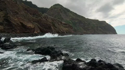 Rugged coastal cliffs and dark volcanic rocks beside the ocean with foamy waves Vidéo 346170156