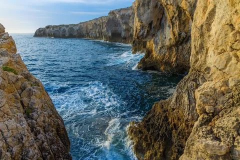 Rugged coastal cliffs meet the deep blue sea with crashing waves Stock Photos