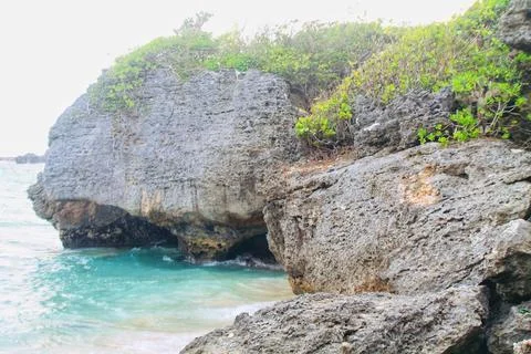 Rugged Coral Rock Cliffs Over Turquoise Ocean Water Geger Beach Bali Stock Photos
