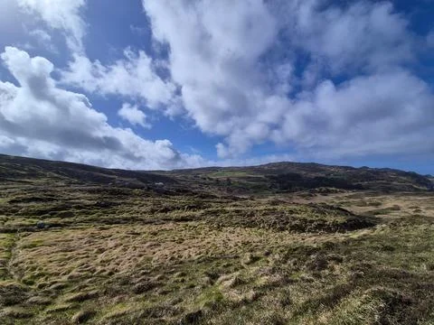 Rugged grassy hillside under dramatic cloudy sky Foto stock