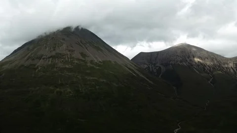 A rugged, green mountain range with a prominent waterfall cascading down a steep Stock Footage 297844143