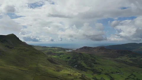 Rugged hills stretching toward a distant lake beneath a partly sunny sky. Stock Footage 314347533