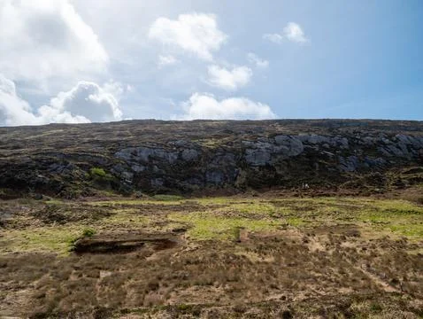 Rugged hillside landscape under a cloudy blue sky Photos