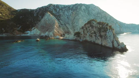 Rugged limestone cliffs meeting the tranquil turquoise sea at sunset Video stock 311572391