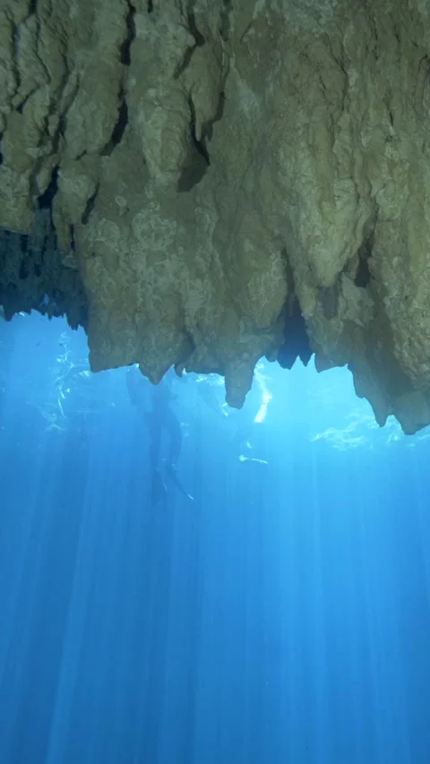 Rugged limestone overhang above blue cenote rays Stock Footage 341396236