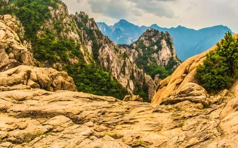 Rugged mountain landscape with dramatic rock formations and green trees und.. Stock Photos