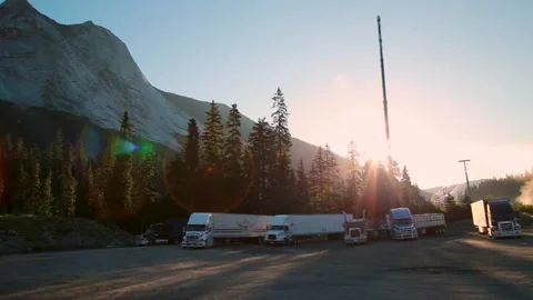 Rugged mountain peak and semi trailers next to Trans Canada highway at sunrise Stock Footage 144409010