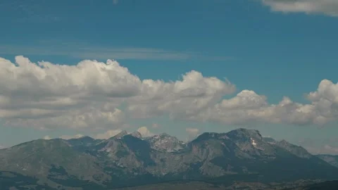 The rugged peaks of the Durmitor mountain range rise beneath towering summer Vídeo Stock 342409547