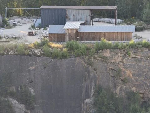 Rugged quarry workshop yard with rusted corrugated metal sheds, stacked concrete Stock Photos