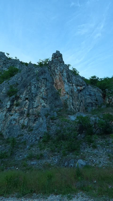 Rugged rock face rises above quiet road. Sicevo Gorge, Serbia. Vertical Vídeos de archivo 337057846